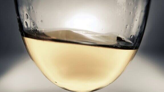创意宏慢动作视频白葡萄酒溅在一个玻璃杯从一边到一边像波浪玻璃与溅起的葡萄酒近距离老式复古风格与愉快轻微柔软褪色