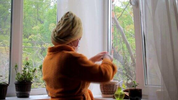冠状病毒戴口罩的妇女独自在家照料室内植物新型冠状病毒肺炎
