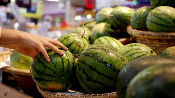 在超市里女人用手挑选新鲜的西瓜