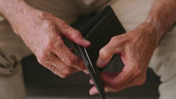 一段4k视频显示一名老年男子在家中查看一个空钱包