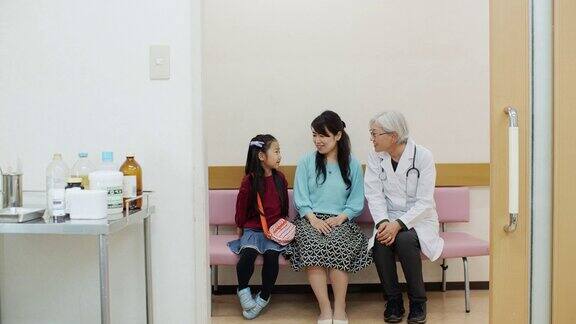 成熟女医生在医院走廊与母亲和孩子交谈