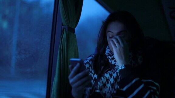 一个拿着手机的女人抓拍到了一个女孩在晚上乘公交车时拿着手机挠脸的照片