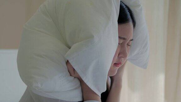 年轻女子在床上睡觉时用枕头捂住耳朵