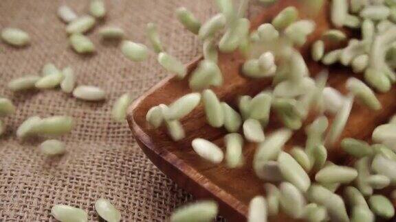 未煮熟的绿色Verdina豆子掉进木制碗里放在粗糙的粗麻布上