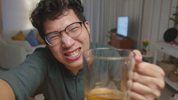 POV屏幕手机:迷人的年轻快乐的亚洲男人享受放松的夜晚派对活动在线庆祝节日与朋友在家里用玻璃杯和瓶子碰杯干杯通过视频电话喝酒