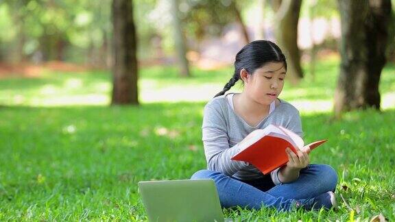 亚洲少年小女孩在大自然中学习对书本的思考