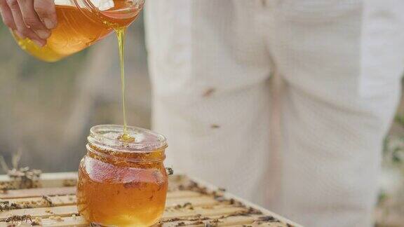 一个养蜂人在玻璃罐中收获金色的蜂蜜