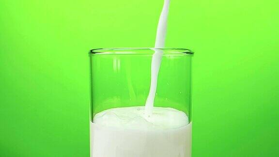 鲜白牛奶倒入杯中色键绿色画面背景慢镜头拍摄饮食和健康营养