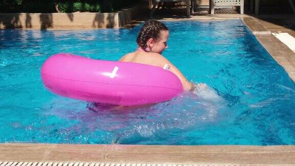 可爱的小女孩在游泳池里玩粉色的充气戒指暑期旅游酒店度假