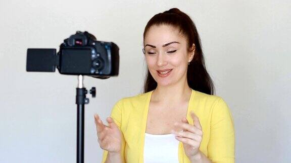 快乐微笑的女人或博主用手势和说话用固定在工作室三脚架上的摄像机录制视频概念-视频视频博客视频博客视频博主博客博客大众媒体和采访