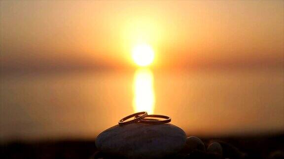 结婚戒指在日落的沙滩上浪漫和爱情