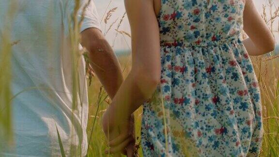 男孩和女孩手牵着手走在农村的草地上