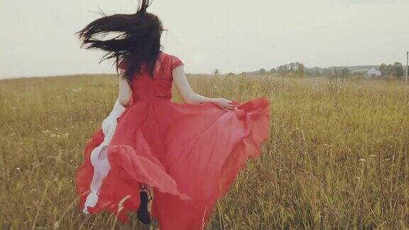 穿着红裙子的漂亮女人跑过秋天的田野慢动作