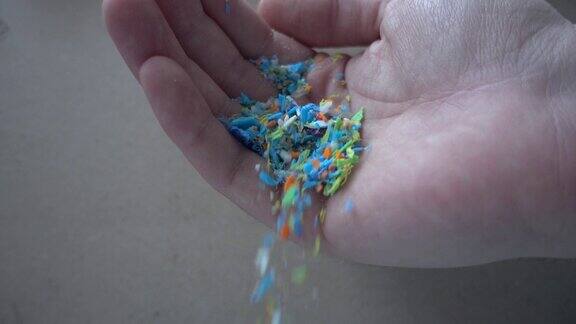微塑料从人手上掉落的侧视图慢动作的垃圾不可回收塑料选择性地聚焦在手上