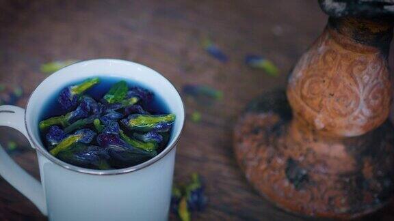 蓝色泰安禅蝴蝶豌豆花茶杯木制的桌子古老的花瓶