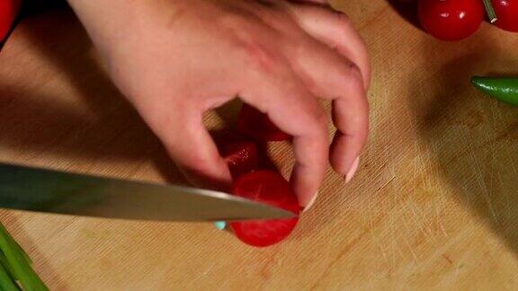特写女孩切樱桃番茄在木砧板上缓慢的运动