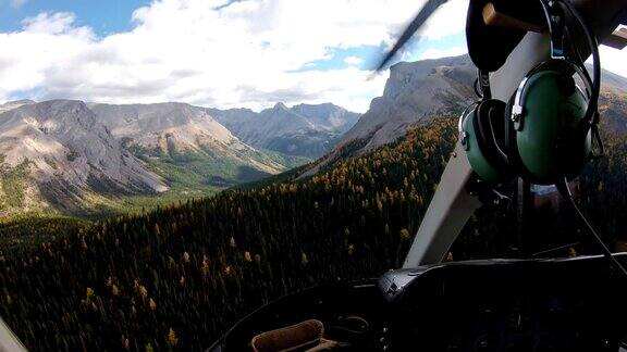 在落基山脉的秋天森林里驾驶直升机的飞行员
