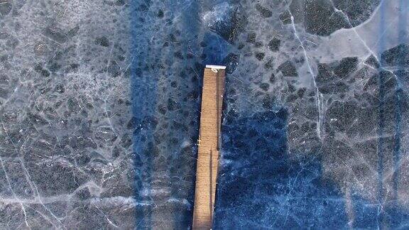 冰湖上木栈桥的天线和冬季冰裂缝