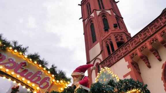 圣诞老人的玩偶在圣诞灯和教堂钟楼旁边
