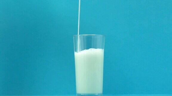新鲜牛奶倒在玻璃上蓝色背景钙和磷的来源