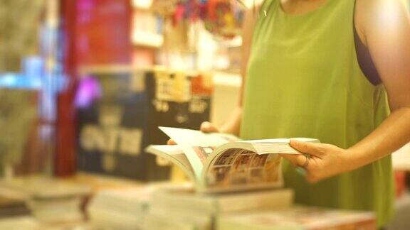 亚洲妇女在书店看书对书架的背景