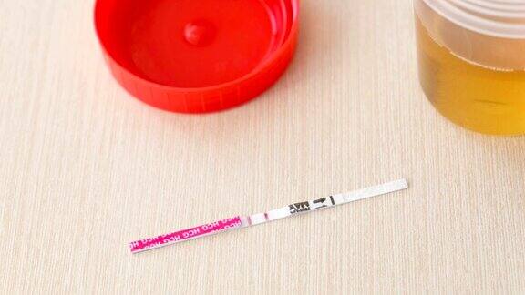 妊娠检查结果呈阳性桌上有两条试纸就在尿罐旁边