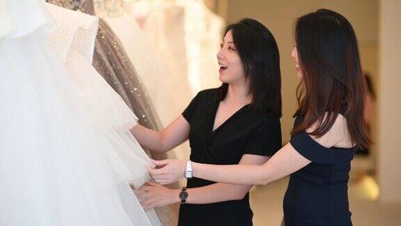 亚洲的中国女新娘和伴娘正在婚纱店为她的婚礼寻找完美的婚纱