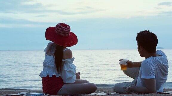 日落时分一对浪漫的情侣坐在海滩上聊天
