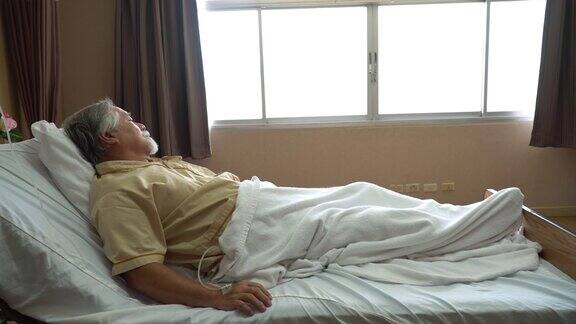 亚洲老年男子病人躺在医院病房的病床上一个孤独的老人在疗养院里看着远方