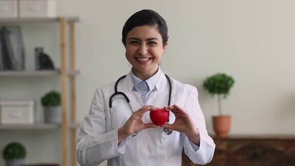 快乐年轻的印度裔女性心脏病学家向镜头展示心脏