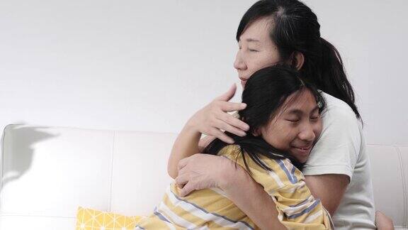 快乐的亚洲女孩拥抱她的母亲坐在一起在家里生活理念