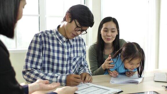 年轻的亚洲夫妇签订合同并购买房子房地产经纪人