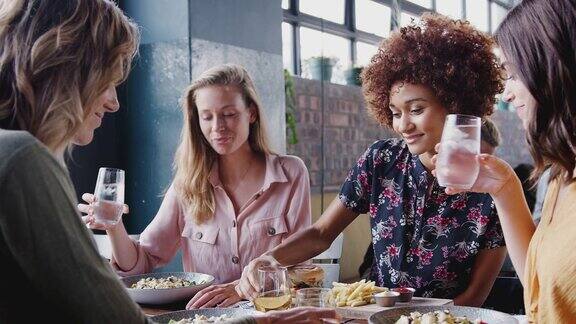 四个女性朋友在餐馆吃饭时用酒敬酒-慢镜头