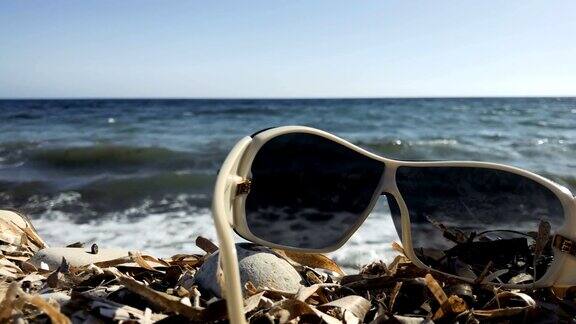 以大海为背景的石头海滩上的太阳镜