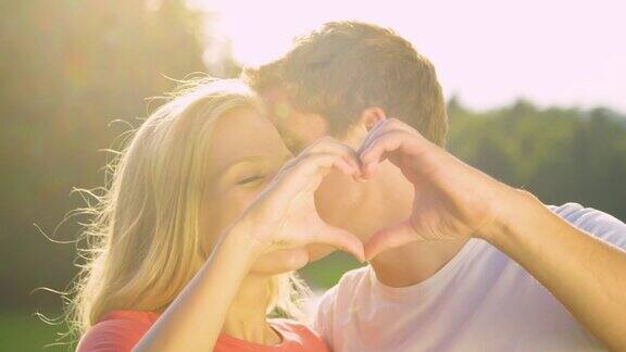 肖像:男子亲吻女友的脸颊同时用手指做心形手势