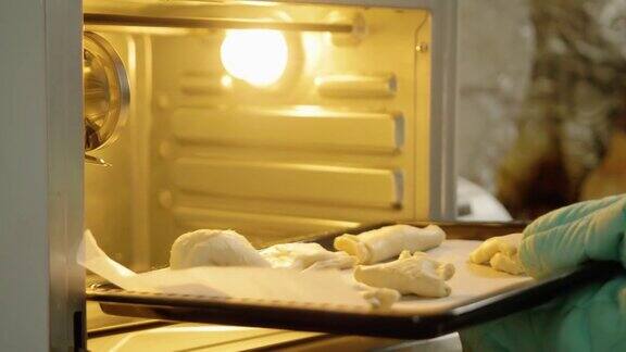 手拿烤箱手套将酥皮托盘放入烤箱准备在家烘焙