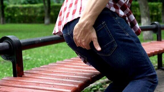 不健康男性感觉痔疮疼痛坐在公园长椅上不舒服