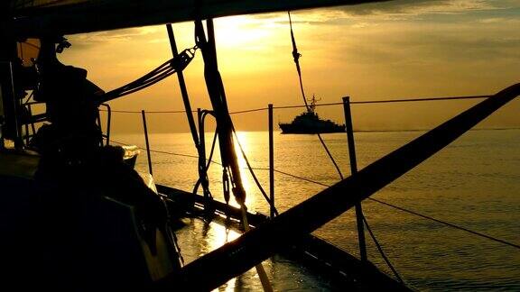 从一艘帆船的侧面看日落背景上的海岸警卫队的船