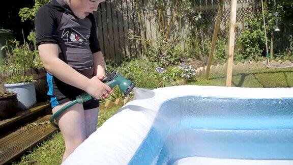 小男孩填满一个充气的浅水池慢动作