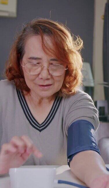 一位老妇人在家里用监测仪测量自己的血压