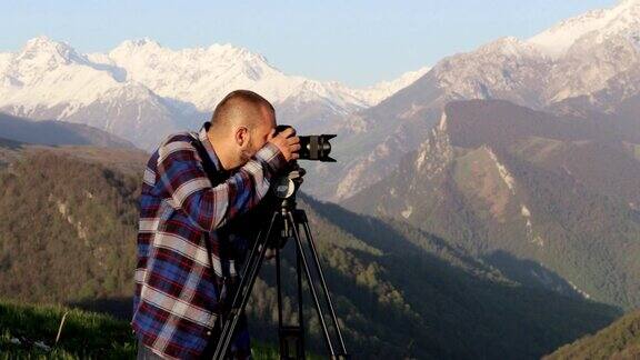 摄影师在山顶上用相机和三脚架拍摄