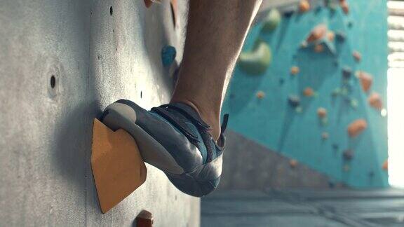 脚的特写在攀岩鞋克服障碍的攀岩墙上慢动作