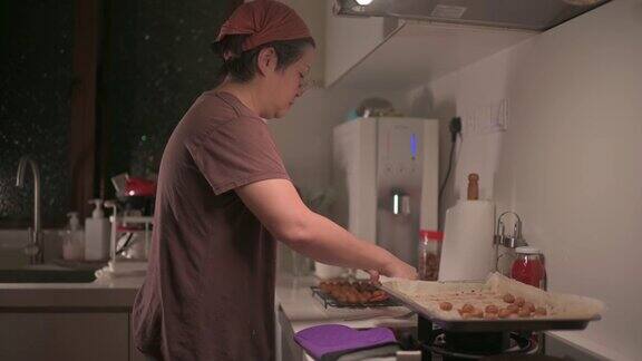亚洲华人中年妇女在厨房拿起烤花生饼干