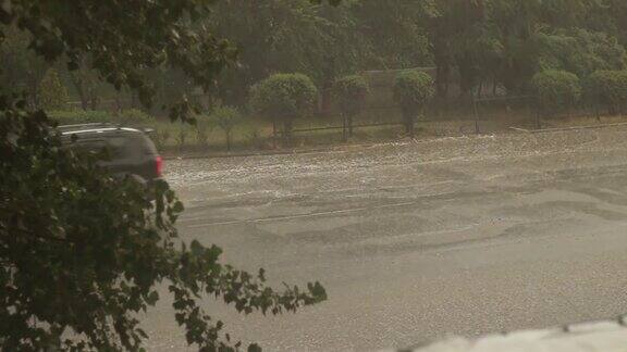 窗外下着大雨暴风雨降临在这个城市汽车在水里穿梭道路被水淹没了