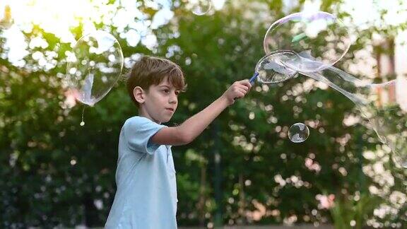 一个小男孩正在后花园玩一根巨大的泡泡棒