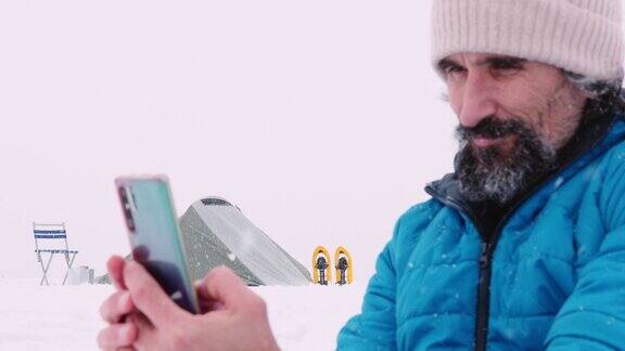 成熟的游客在冬季山地露营时使用手机独自在大自然中