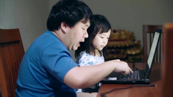 快乐的父亲和女儿使用笔记本电脑在家里学习