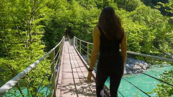年轻女子走在一座木制吊桥上
