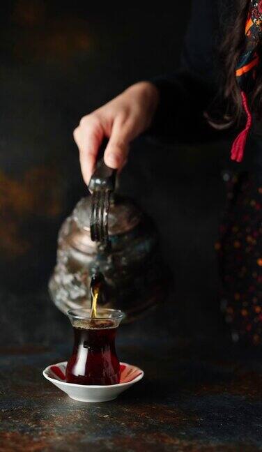 年轻的农妇服务传统的土耳其红茶与旧服务托盘