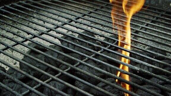 一名白人男子的手把一根点燃的木火柴扔进一个户外烧烤架点燃煤块准备烧烤